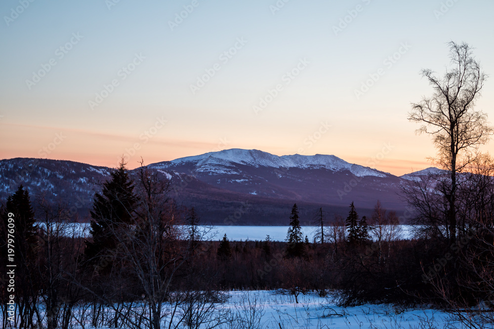 The mountain range and the frozen lake at sunset in the winter