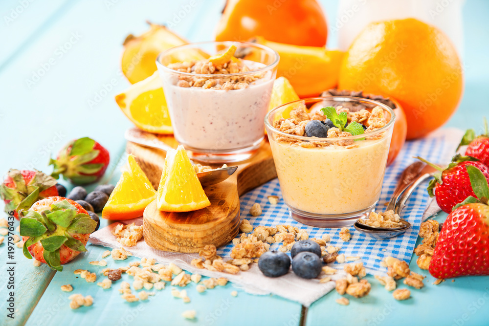 Orange persimmon blueberry smoothie with granola and fruits. Selective focus. Copy space Orange persimmon blueberry smoothie with granola and fruits. Selective focus. Copy space