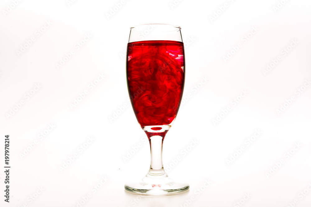 Red food coloring diffuse in water inside wine glass with empty copy-space area for slogan or advertising text message, over isolated white background. Red food coloring diffuse in water inside wine glass with empty copy-space area for slogan or advertising text message, over isolated white background.