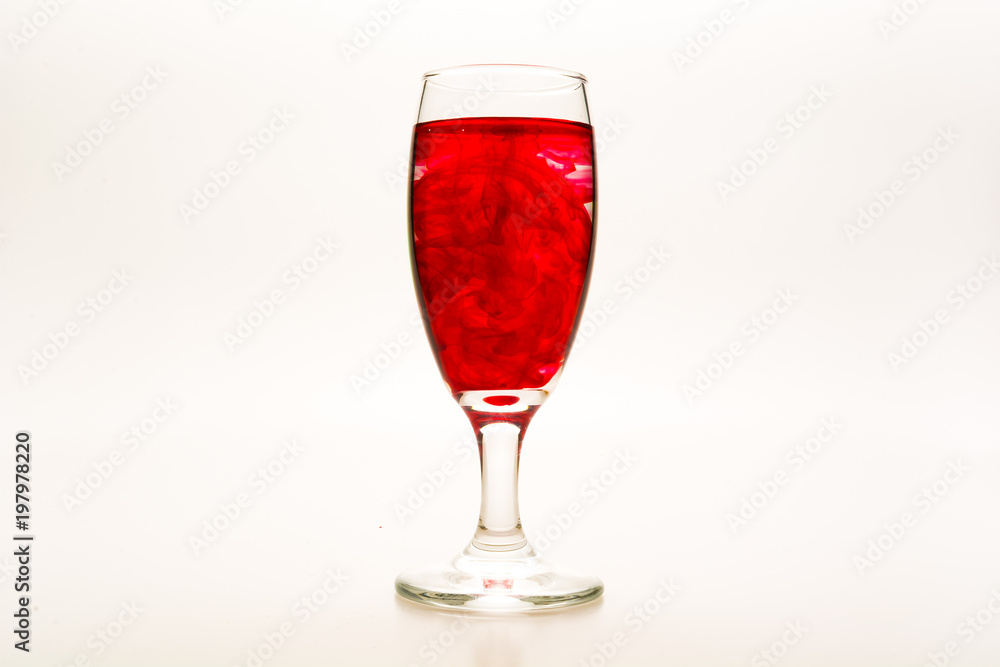 Red food coloring diffuse in water inside wine glass with empty copy-space area for slogan or advertising text message, over isolated white background. Red food coloring diffuse in water inside wine glass with empty copy-space area for slogan or advertising text message, over isolated white background.