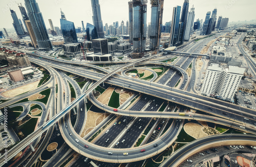 Fototapeta premium Widok z lotu ptaka na duże skrzyżowanie autostrad z ruchem w Dubaju, ZEA, w dzień. Malowniczy pejzaż. Kolorowe tło transportu, komunikacji i jazdy.