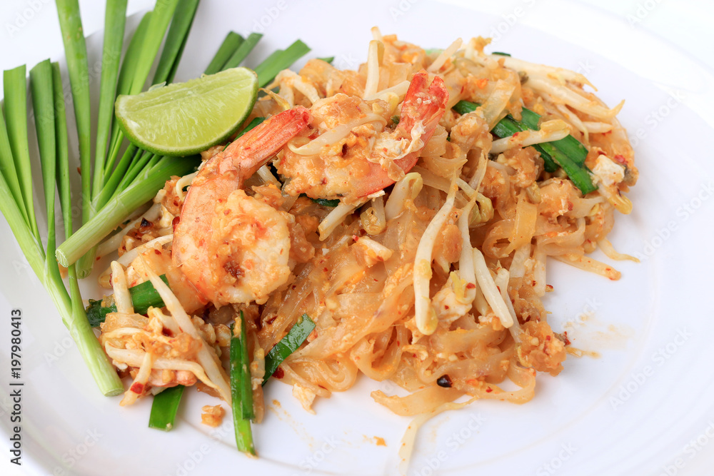Pad Thai, stir-fried rice noodles with shrimp in white plate with slide lemon and green vegetable. The one of Thailand's national main dish. the popular food in Thailand. Thai Fried Noodles Pad Thai, stir-fried rice noodles with shrimp in white plate with slide lemon and green vegetable. The one of Thailand's national main dish. the popular food in Thailand. Thai Fried Noodles