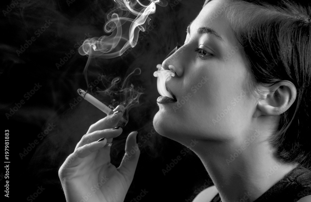 Beautiful young woman smoking a cigarette on black background Stock ...
