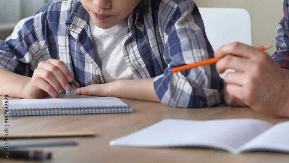 Father and son doing homework together, preparing for difficult quiz, close up Father and son doing homework together, preparing for difficult quiz, close up