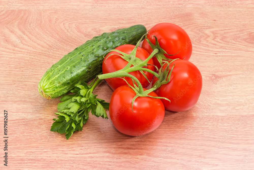 Tomatoes on branch, cucumber and parsley on a wooden surface Tomatoes on branch, cucumber and parsley on a wooden surface