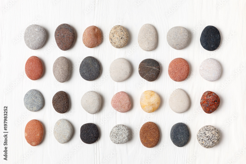 Pattern of natural multicolored pebbles on white wooden background. - obrazy, fototapety, plakaty 
