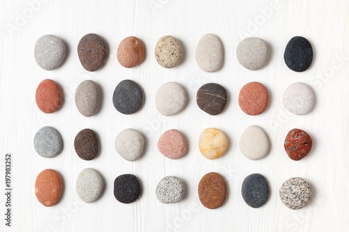 Bilde på lerret Pattern of natural multicolored pebbles on white wooden background