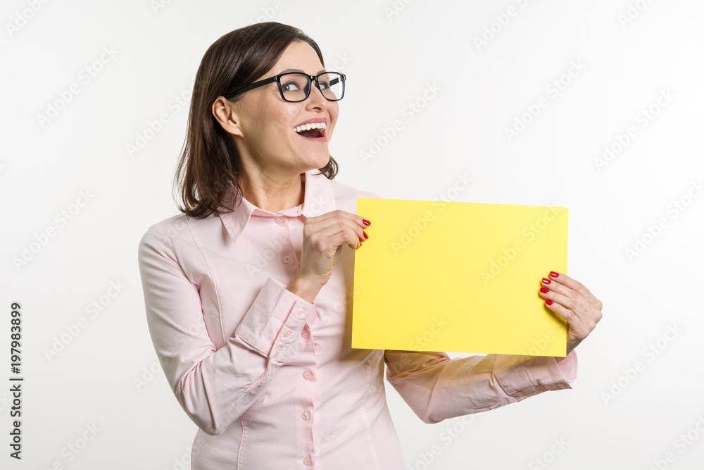 Smiling middle aged woman with yellow sheet of paper on white background Smiling middle aged woman with yellow sheet of paper on white background