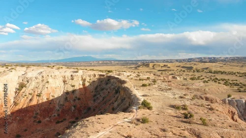 Aerial shot flying toward people hiking along an incredible canyon rim trail in the desert