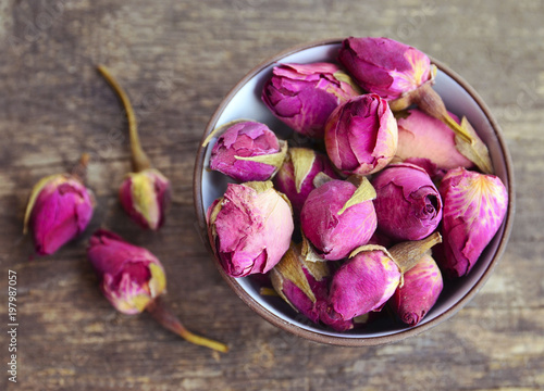 Dry rose buds flowers in a bowl on old wooden table.Healthy herbal drinks concept.Asian ingredient for aromatherapy tea.Selective focus.