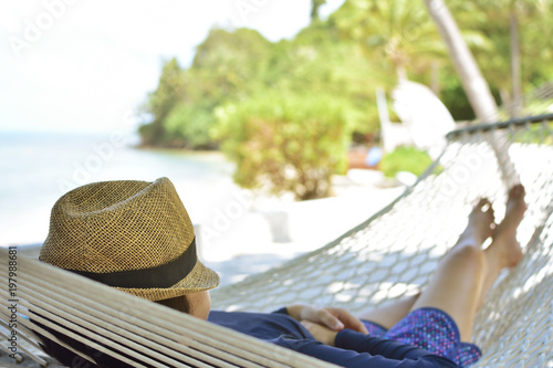 Woman relaxing on hammock with hat on vacation
