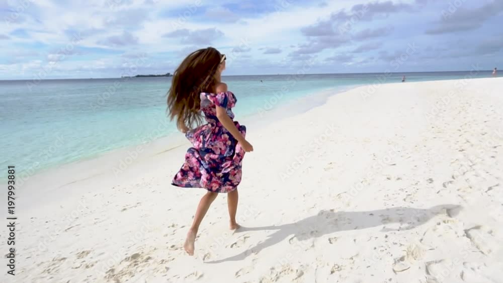 Woman running and raising hands on beach with blue water of ocean in Maldives Woman running and raising hands on beach with blue water of ocean in Maldives