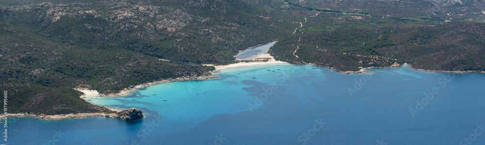 Aerial image of turquoise blue waters at the Corsican coastline West of Saint-Florent showing Punta Cavallata and Plage du Lotu