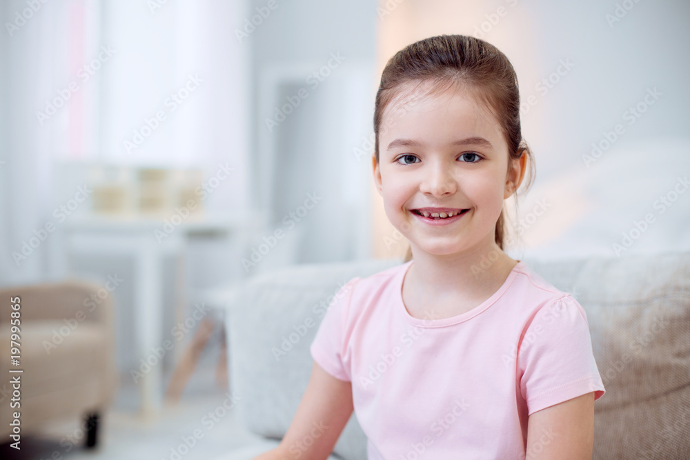 Sincere smile. Positive energetic nice girl grinning whole staring at camera and posing on blurred background Sincere smile. Positive energetic nice girl grinning whole staring at camera and posing on blurred background