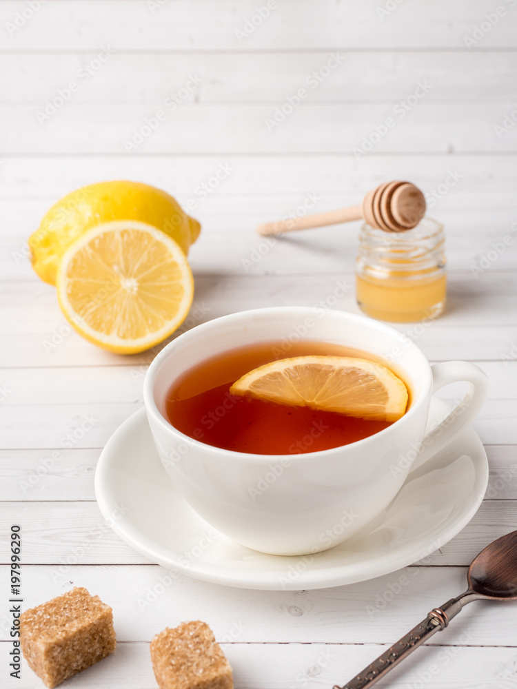 Herbal black tea in a white Cup, honey in a jar of fresh lemon on white wooden background Herbal black tea in a white Cup, honey in a jar of fresh lemon on white wooden background