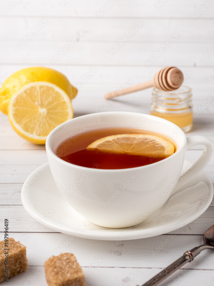 Herbal black tea in a white Cup, honey in a jar of fresh lemon on white wooden background Herbal black tea in a white Cup, honey in a jar of fresh lemon on white wooden background