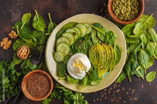 Green salad with spinach, cucumber, avocado, egg, flax and pumpkin seed. Food background. Detox Vegetarian Healthy Food Concept. Top view, copy space.