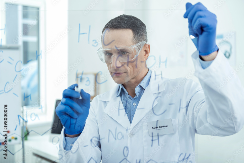 My research. Handsome concentrated dark-haired smart scientist thinking and wearing a uniform and writing formulas My research. Handsome concentrated dark-haired smart scientist thinking and wearing a uniform and writing formulas