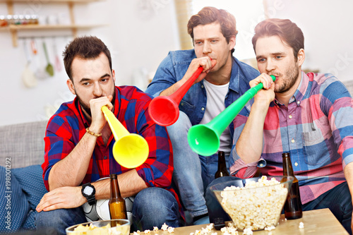 Happy male friends cheering and watching sports on tv photo