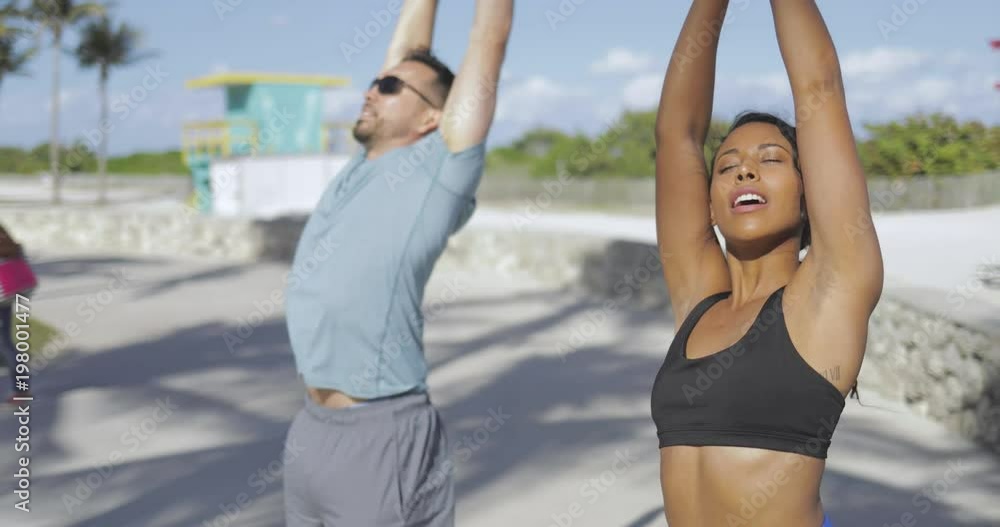 Sportive black girl and man in sportswear training together and stretching all body standing in sunlight. Sportive black girl and man in sportswear training together and stretching all body standing in sunlight.