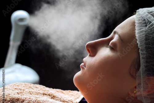 Obraz na plátne Beauty treatment of face skin with ozone facial steamer in spa center