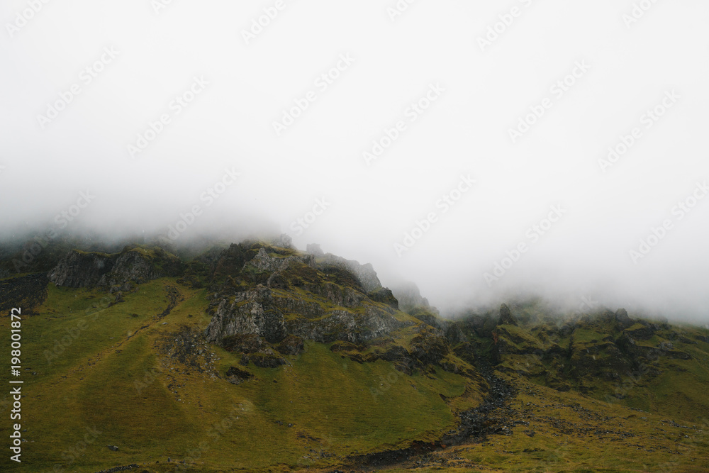 majestic rocky hills covered with green moss in fog, iceland