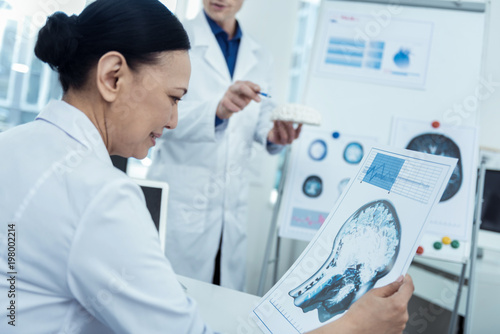 Check it up. Nice asian female doctor holding brain image while thinking out future surgery