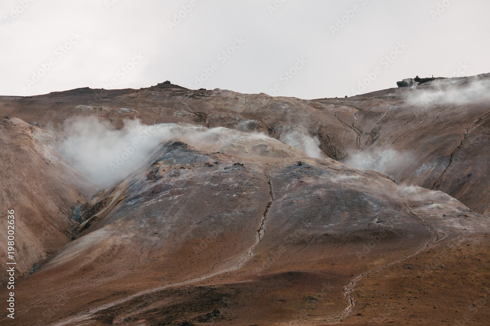 magnificent landscape with hills and hot spring with steam in iceland