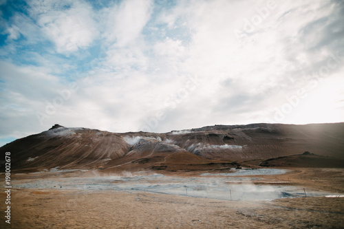 majestic landscape with hills and hot spring with steam in iceland