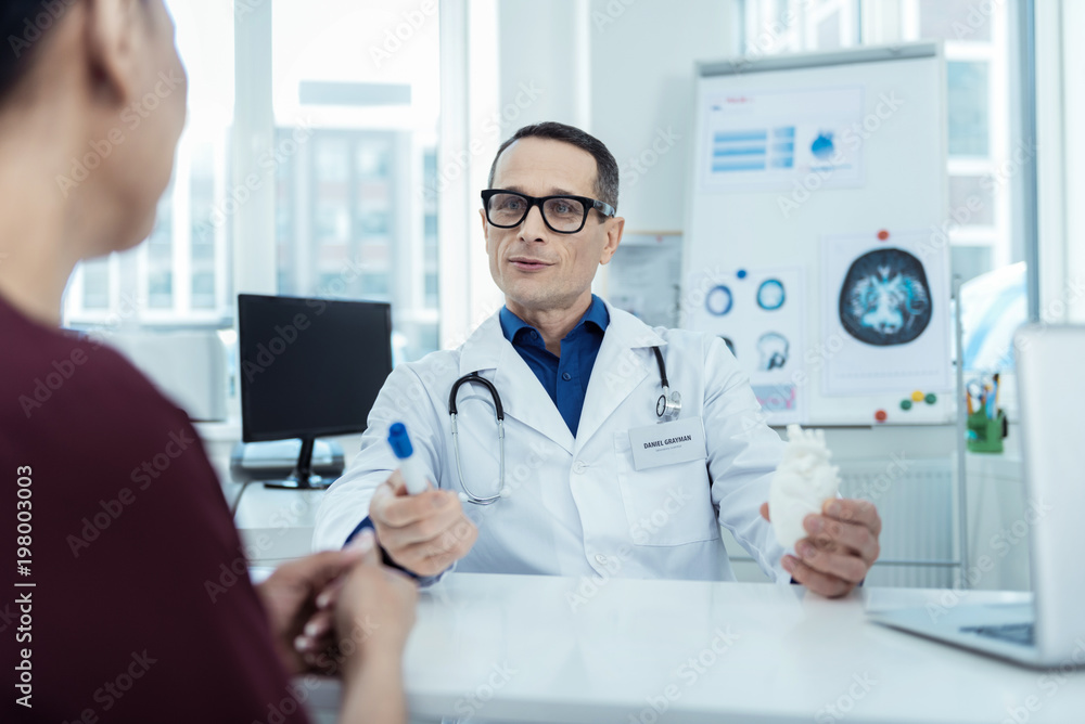 Fototapeta premium Medical world. Professional doctor sitting at the table and talking to her patient