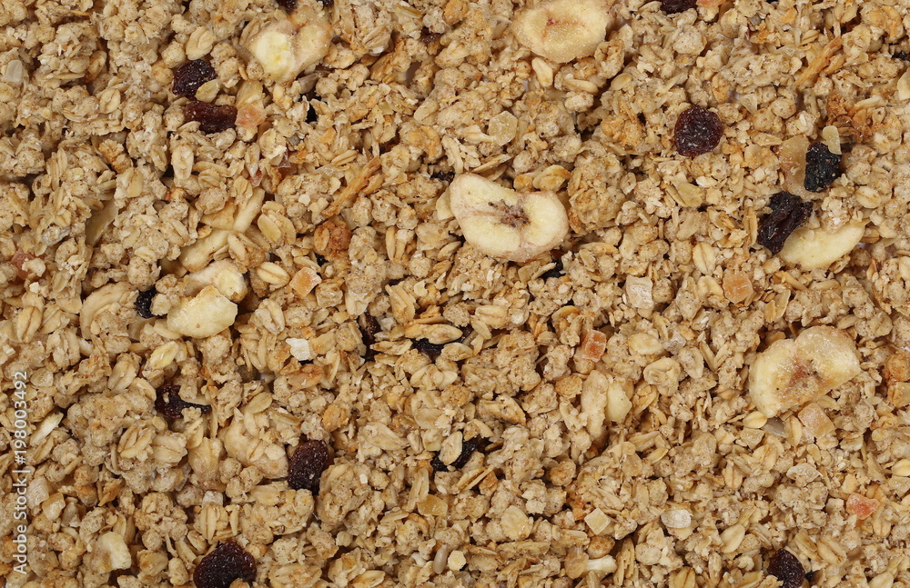 Crunchy granola, muesli pile with banana, pineapple slices, peanuts and raisins background and texture Crunchy granola, muesli pile with banana, pineapple slices, peanuts and raisins background and texture