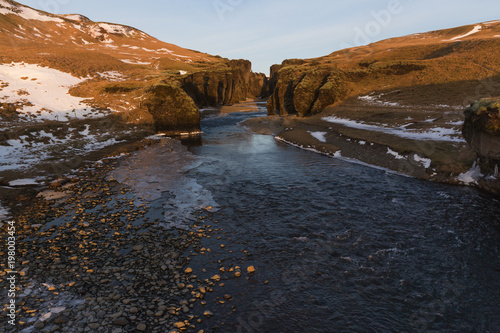 beautiful icelandic landscape with cold river, rocks and snow, fjadrargljufur, iceland