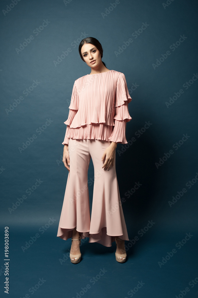 Attractive caucasian female model wearing elegant dress for work or dinner with blue background.Studio shot. Attractive caucasian female model wearing elegant dress for work or dinner with blue background.Studio shot.