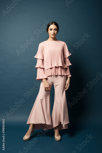 Attractive caucasian female model wearing elegant dress for work or dinner with blue background.Studio shot.