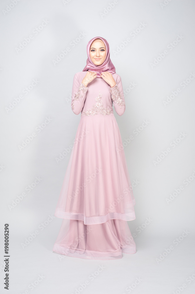 Attractive young Muslim girl wearing pink dress and hijab with grey background.Hijab Fashion Portraiture. Attractive young Muslim girl wearing pink dress and hijab with grey background.Hijab Fashion Portraiture.