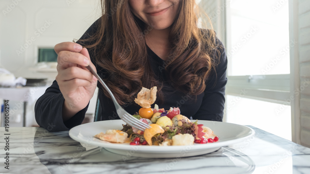 A beautiful asian woman enjoy eating fruits salad on the table in restaurant A beautiful asian woman enjoy eating fruits salad on the table in restaurant