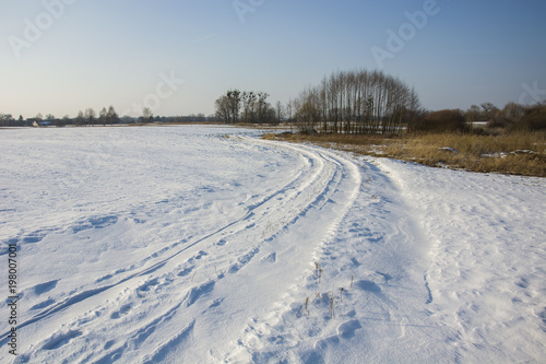 Winding snowy road in field and grove