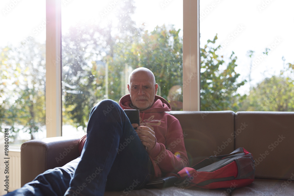 Older man in sofa using mobile phone Older man in sofa using mobile phone