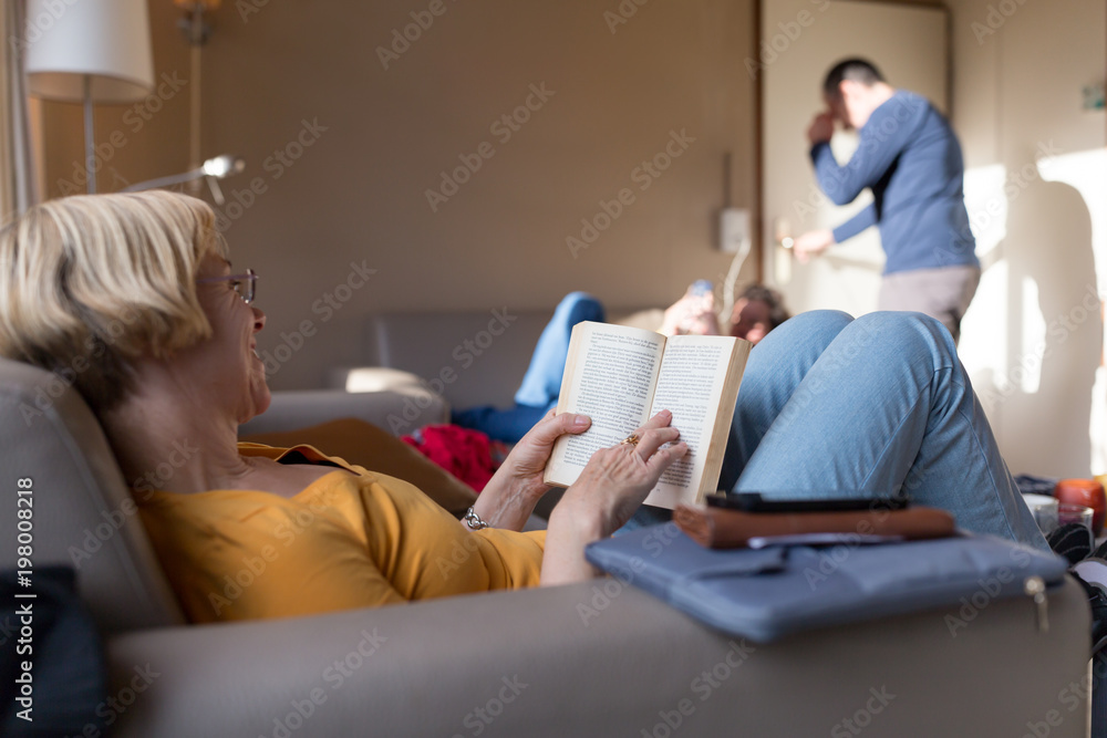 Woman reading a book while lying on sofa Woman reading a book while lying on sofa