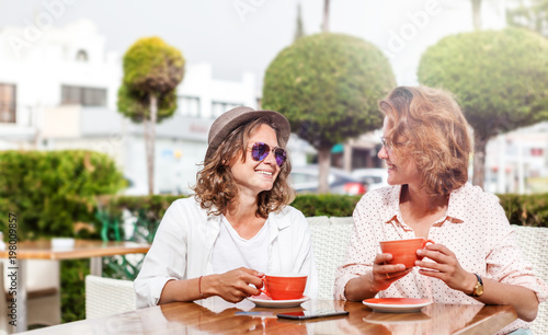 Two young attractive women girlfriends girls are sitting in a cafe  chatting with a cup of coffee  friendship  communication  travel and vacations