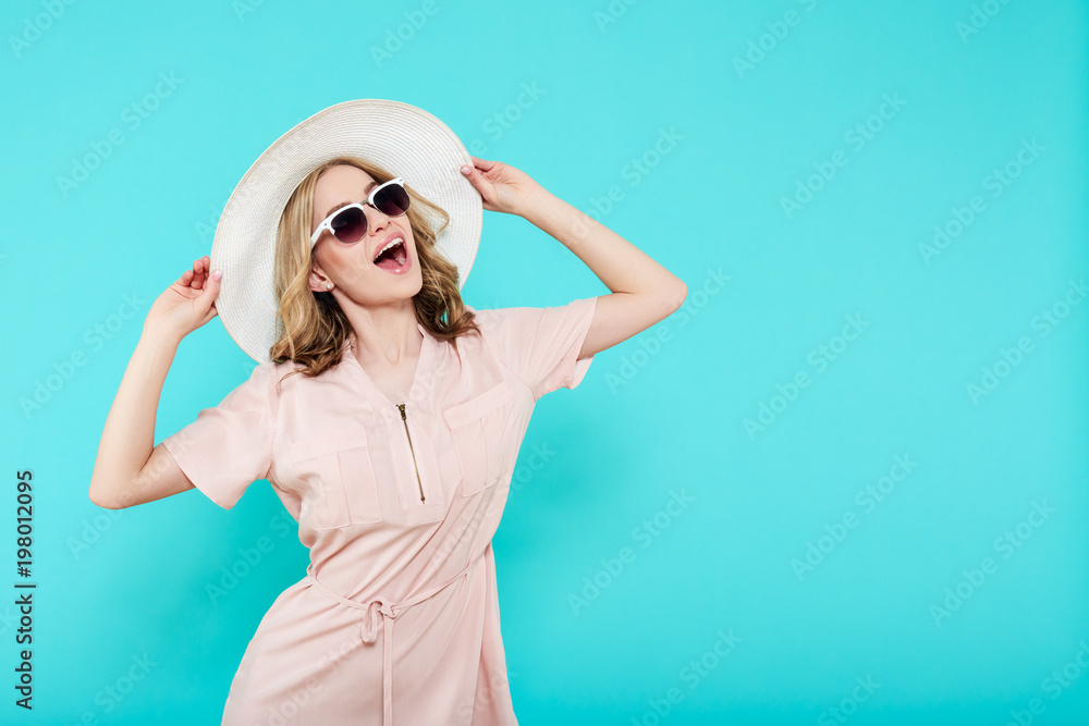 Beautiful young woman in elegant pale pink dress, sunglasses and summer hat. Studio portrait of fashionable woman over pastel blue background. Summer Vacation concept. Beautiful young woman in elegant pale pink dress, sunglasses and summer hat. Studio portrait of fashionable woman over pastel blue background. Summer Vacation concept.