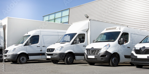 delivery white vans in service van trucks and cars in front of the entrance of a warehouse distribution logistic society