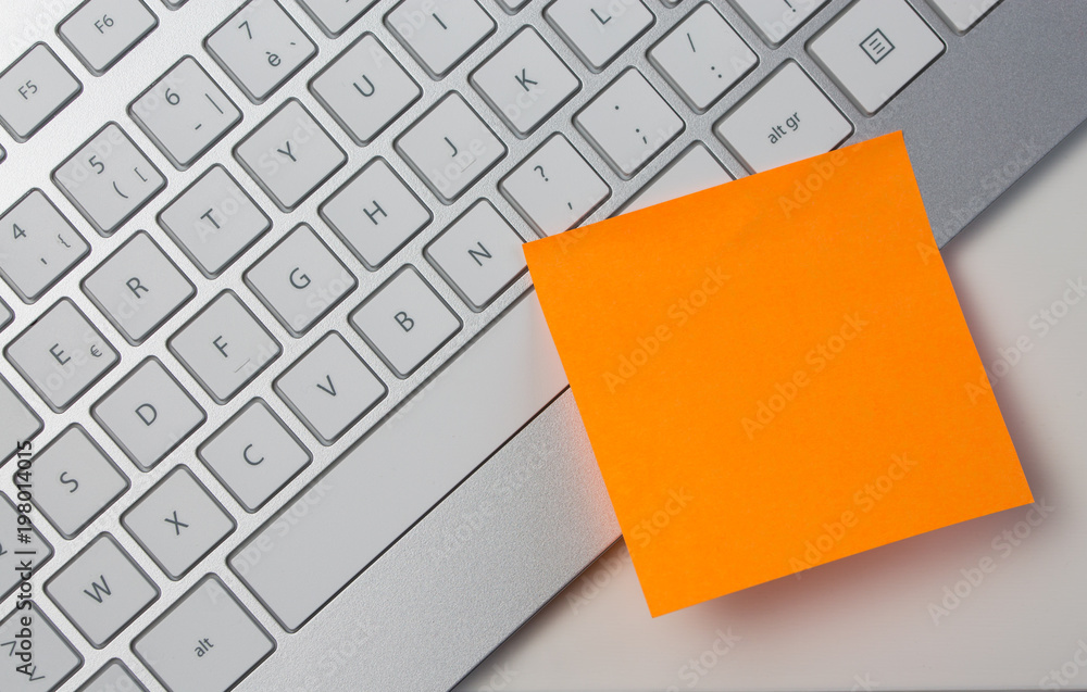 Blank sticky note pasted on keyboard at work table Blank sticky note pasted on keyboard at work table