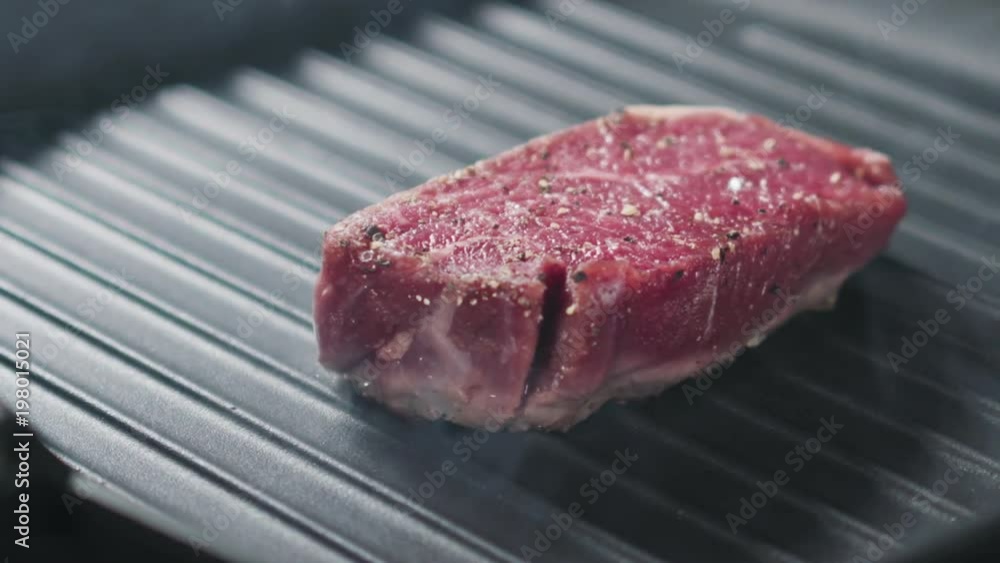 Slow motion slide shot of preparing steak filet mignon on a grill pan Slow motion slide shot of preparing steak filet mignon on a grill pan