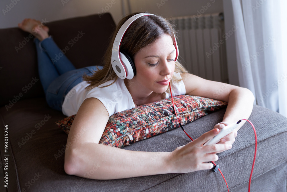 Sticker Beautiful young woman listening to music with mobile phone at home