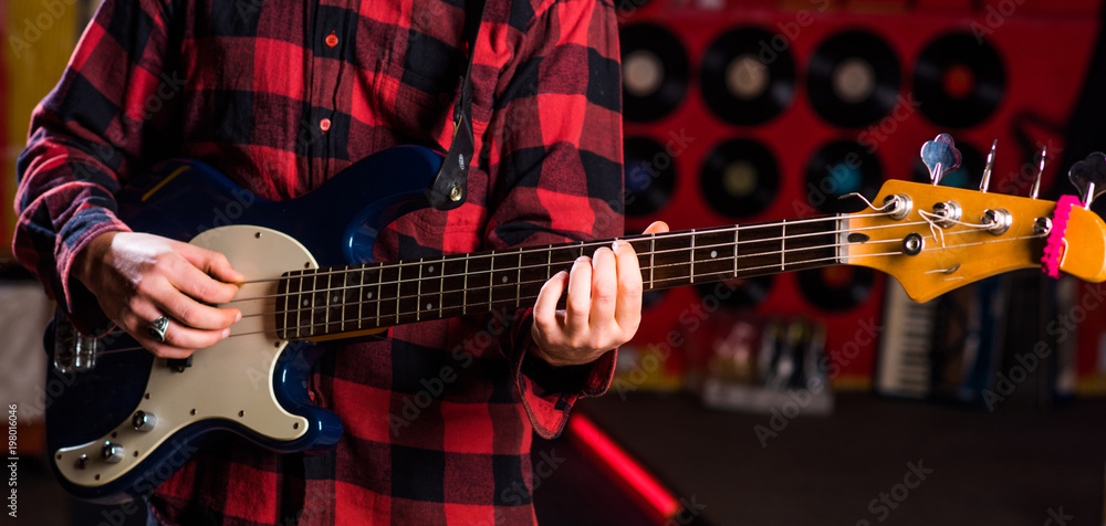 Fototapeta premium Male hands hold guitar, play music in club atmosphere background.