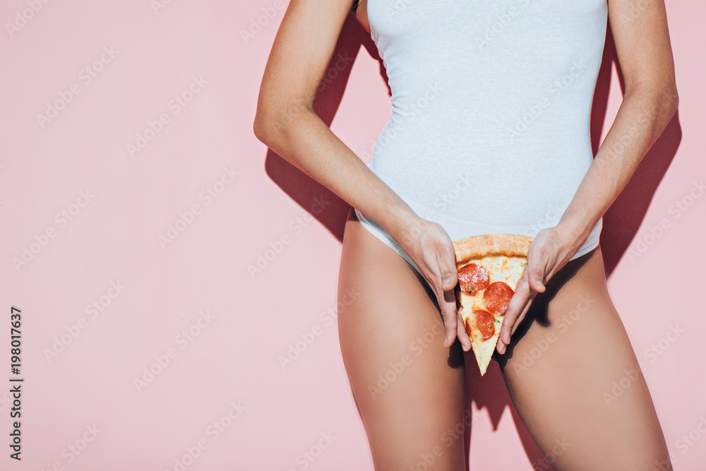 Φωτογραφία partial view of woman in white bodysuit holding piece of italian pizza on pink b