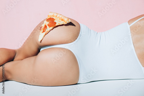 partial view of piece of pizza on female booty photo