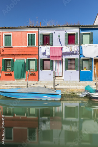 Typical canal and colorful facades with vibrant colors and laundry drying in famous fishermen village on the island of Burano  Venice  Italy