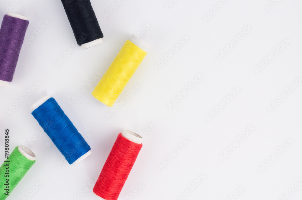 Scattered bobbins of new colorful threads on white background. Top view Scattered bobbins of new colorful threads on white background. Top view